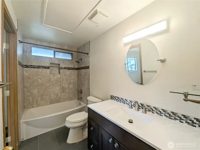 a bathroom with a bathtub shower sink vanity mirror and toilet