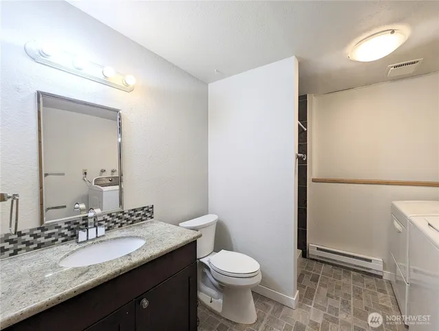 a bathroom with a granite countertop sink toilet and mirror