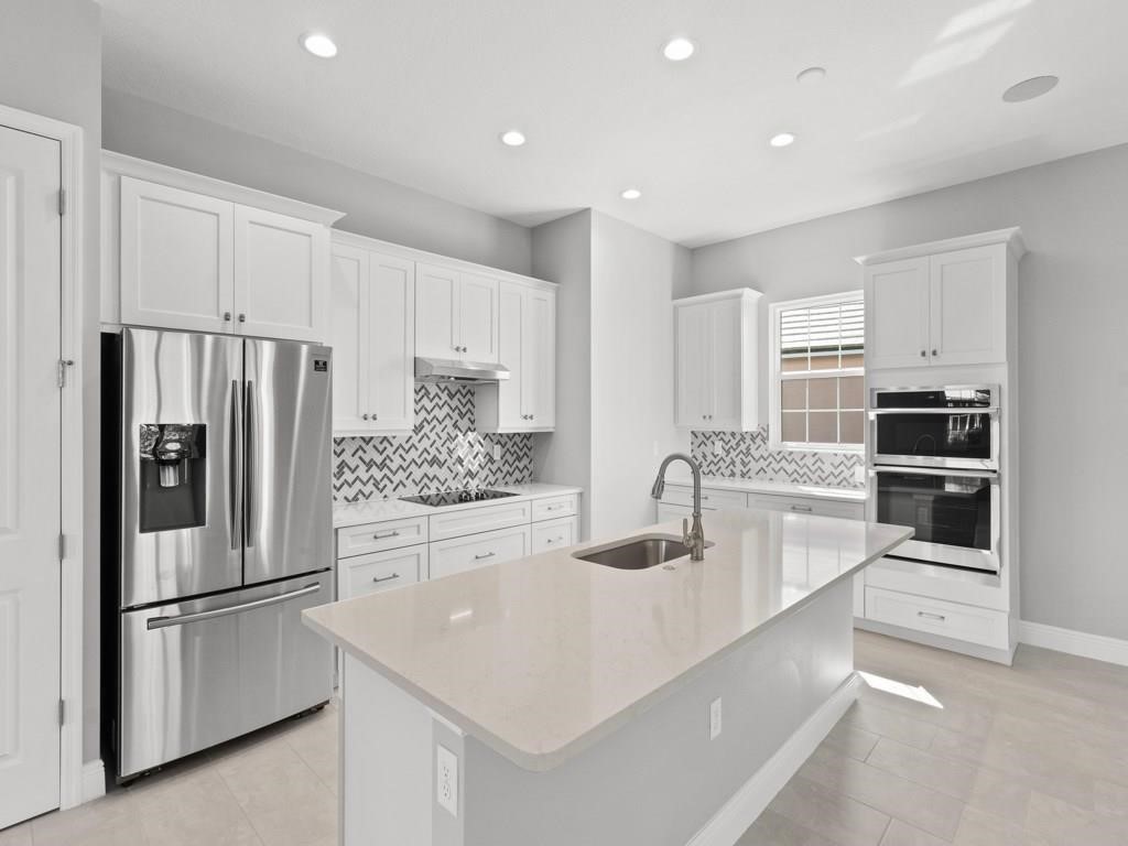 a kitchen with stainless steel appliances granite countertop a refrigerator a stove and a sink