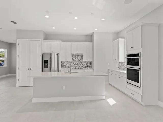 a large white kitchen with stainless steel appliances