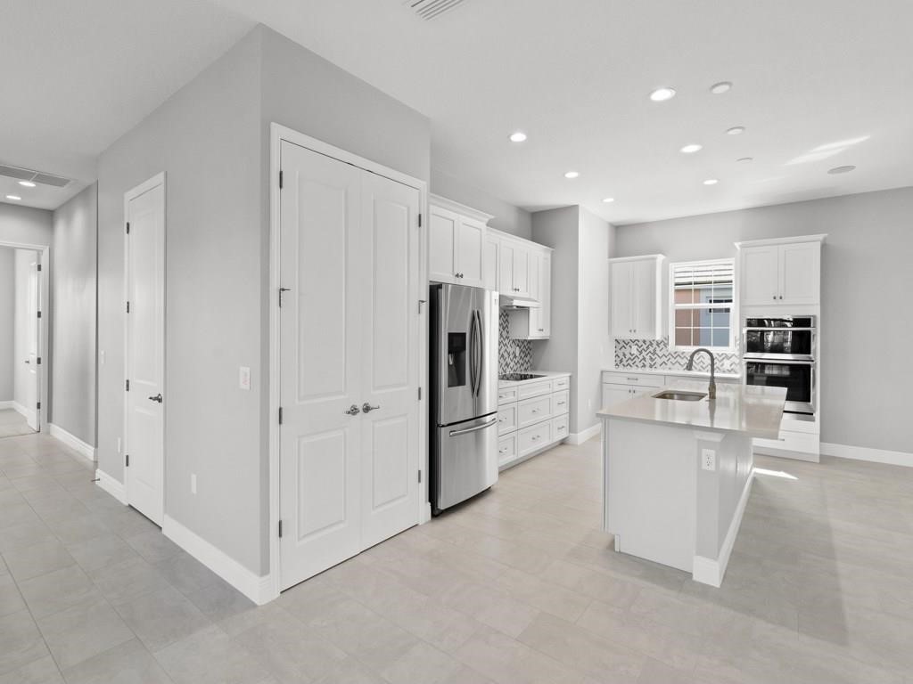 1891 East Cayman Road Vero Beach, FL 32963 - Photo 12 of 27 a kitchen with white cabinets and stainless steel appliances