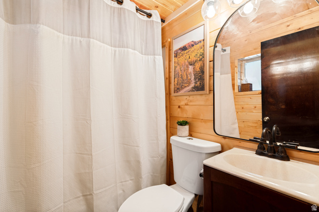 11237 East Aspen Road, Unit 74 Heber City, UT 84032 - Photo 23 of 32 Wood-paneled bathroom featuring an integrated sink vanity with a dark wood-finish cabinet and a wall-mounted mirror