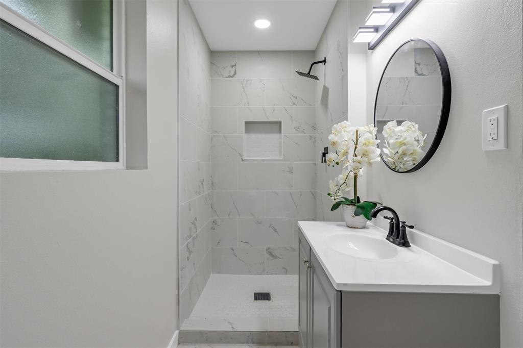 4815 Kelman Street Dallas, TX 75214 - Photo 25 of 37 Bathroom featuring a walk-in shower with large format tile, a built-in shower niche, and a matte black rain showerhead