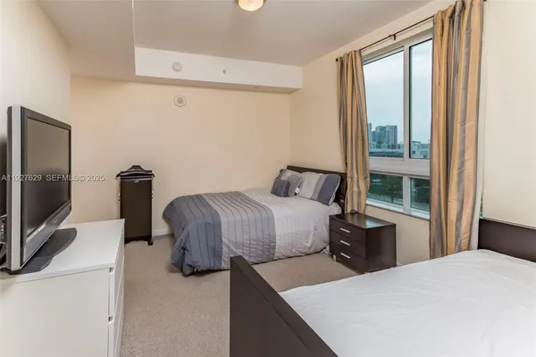 a bedroom with a bed and a flat tv screen on the dresser