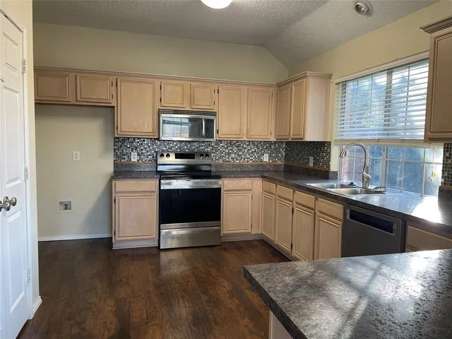 a kitchen with stainless steel appliances granite countertop a stove a sink dishwasher and a refrigerator