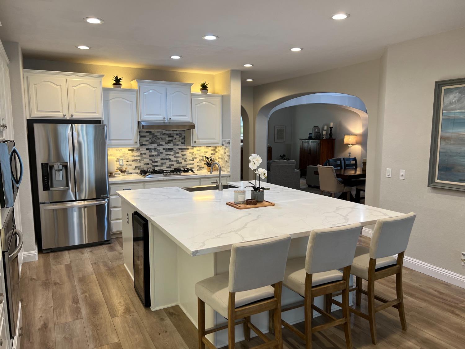 1135 North Perry Avenue Clovis, CA 93611 - Photo 6 of 27 a kitchen with stainless steel appliances a dining table chairs refrigerator and microwave