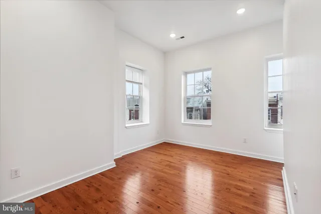 an empty room with wooden floor and windows
