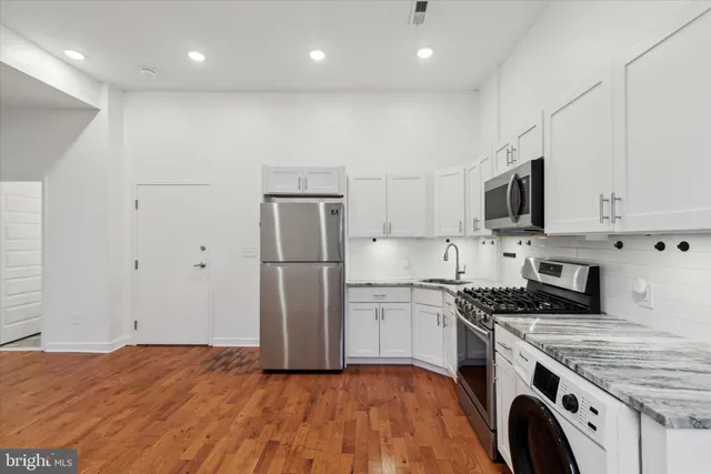 a kitchen with kitchen island granite countertop appliances cabinets and a sink