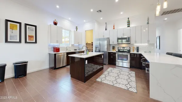 a kitchen with stainless steel appliances kitchen island granite countertop a sink counter space cabinets and a refrigerator