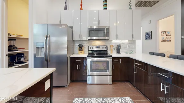a kitchen with stainless steel appliances kitchen island granite countertop a refrigerator a sink a stove and white cabinets