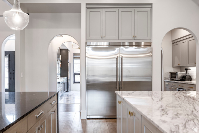 3247 South Mapleton Estates Drive Mapleton, UT 84664 - Photo 29 of 70 Kitchen featuring arched walkways, dark stone counters, stainless steel appliances, gray cabinets, and light wood-type flooring