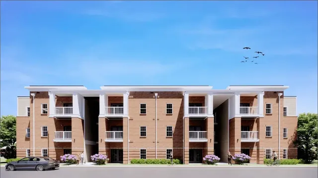 a front view of a building with lot of cars and trees