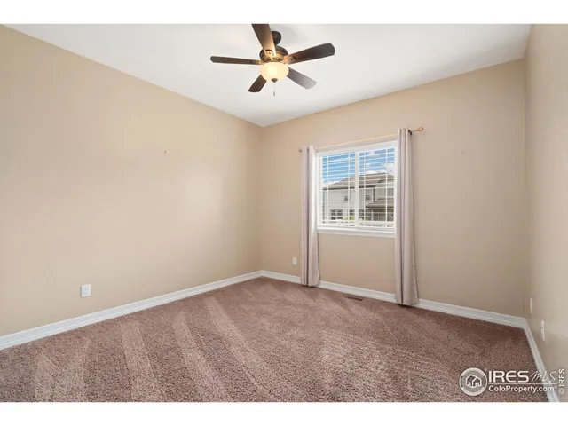 an empty room with windows and ceiling fan