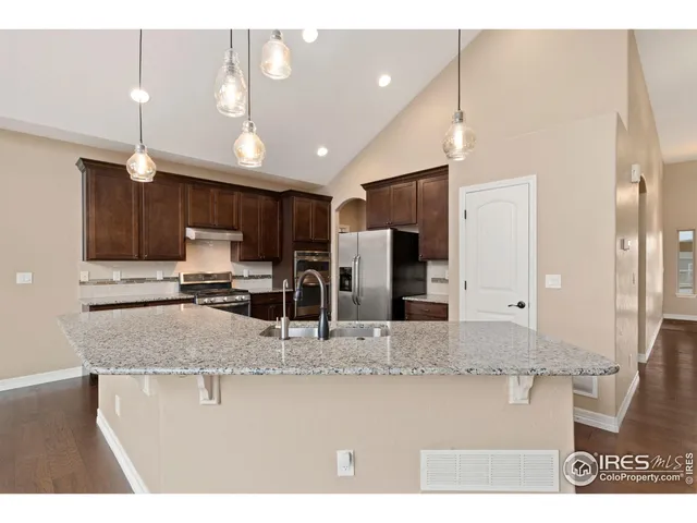 a kitchen with stainless steel appliances granite countertop a sink refrigerator and cabinets