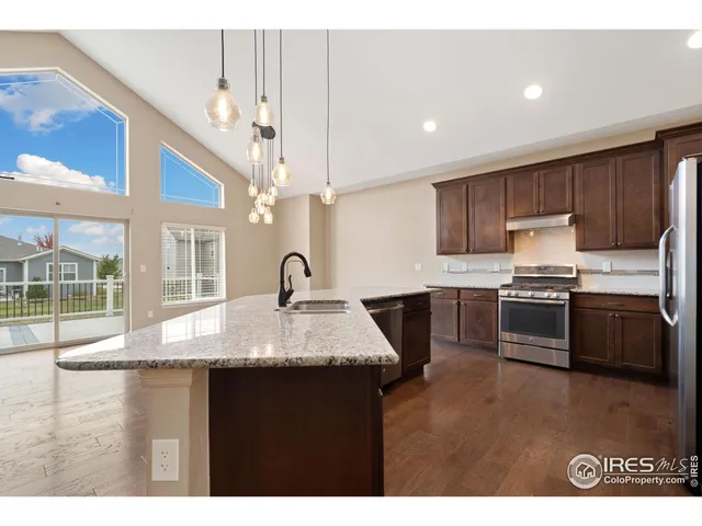 a kitchen with granite countertop a stove a sink and a refrigerator