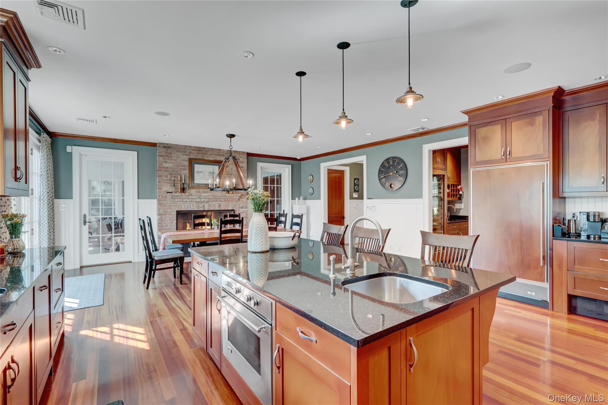 63 Dyke Road Setauket, NY 11733 - Photo 11 of 49 Kitchen with dark stone counters, oven, brown cabinetry, an island with sink, and light wood-style floors