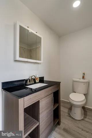 a bathroom with a granite countertop sink and a toilet