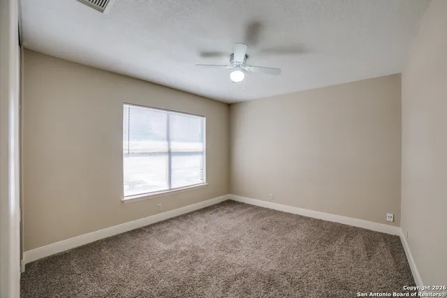 an empty room with a window and a fan