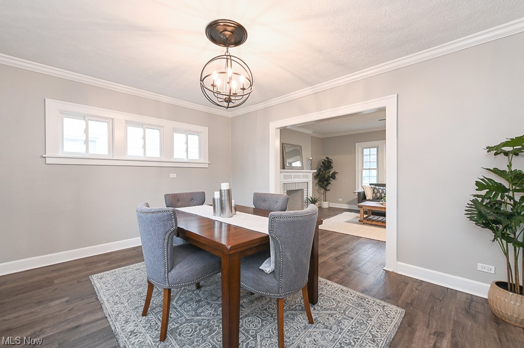 Dining area with ornamental molding, dark wood-type flooring, plenty of natural light, and a chandelier
