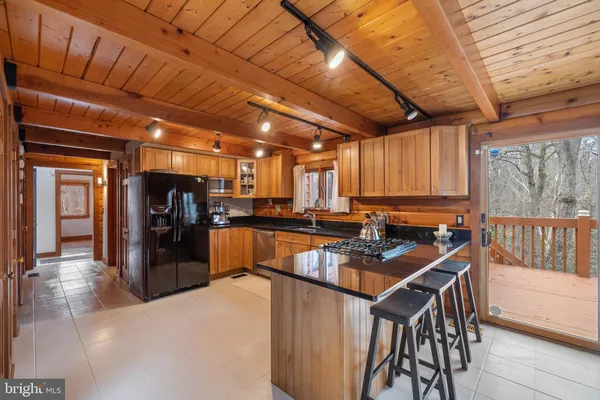 a kitchen with stainless steel appliances granite countertop a stove a refrigerator a sink a dining table and chairs with wooden floor