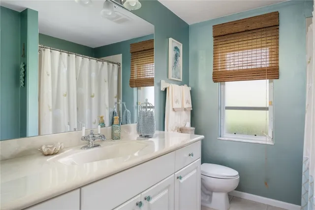 a bathroom with a granite countertop sink toilet and mirror