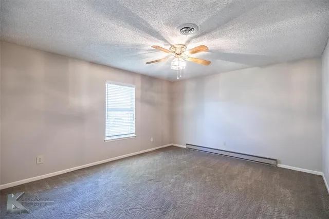 an empty room with windows and fan