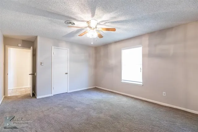an empty room with windows and fan