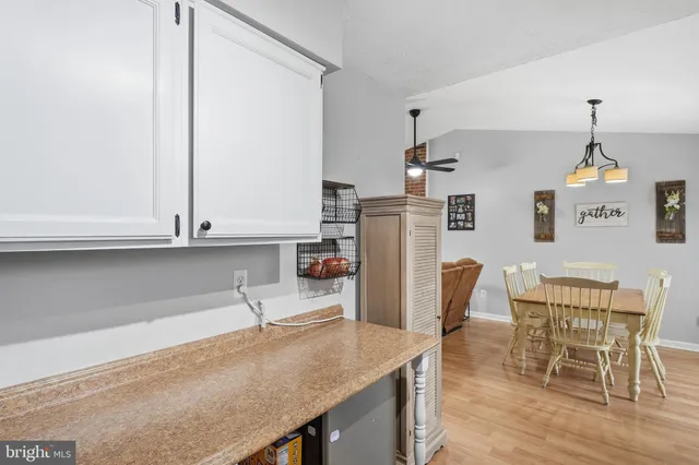 a kitchen with stainless steel appliances granite countertop a refrigerator a stove top oven a dining table and chairs with wooden floor