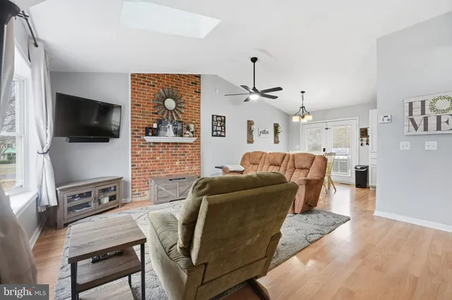 a living room with furniture a flat screen tv and kitchen view
