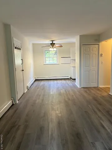 an empty room with wooden floor closet and windows