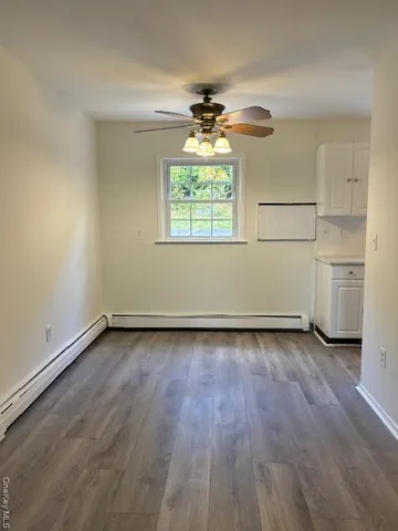an empty room with wooden floor cabinet and a window