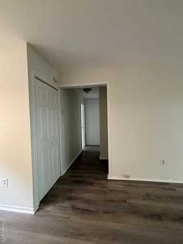 a view of an empty room with wooden floor and closet