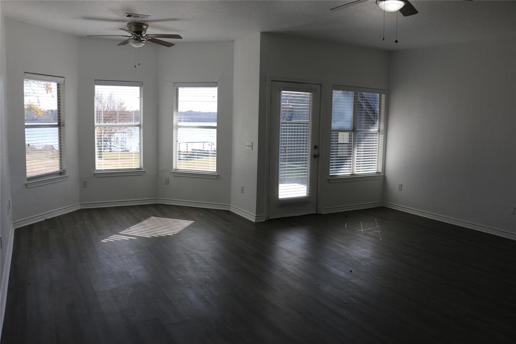2858 Waters Edge Quinlan, TX 75474 - Photo 12 of 34 an empty room with wooden floor chandelier fan and windows