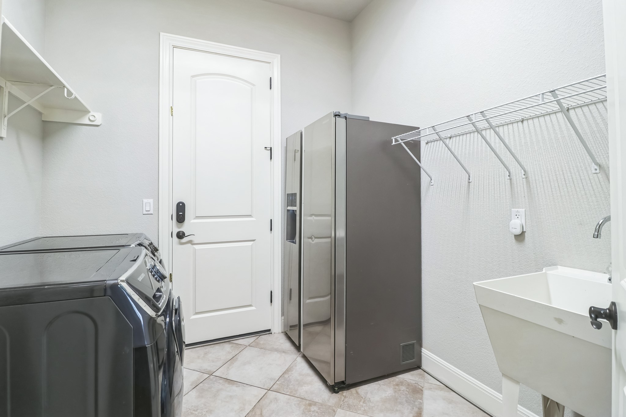 3913 Remington Road Cedar Park, TX 78613 - Photo 17 of 32 Tiled flooring and a utility sink complement this functional and well-equipped laundry room space.