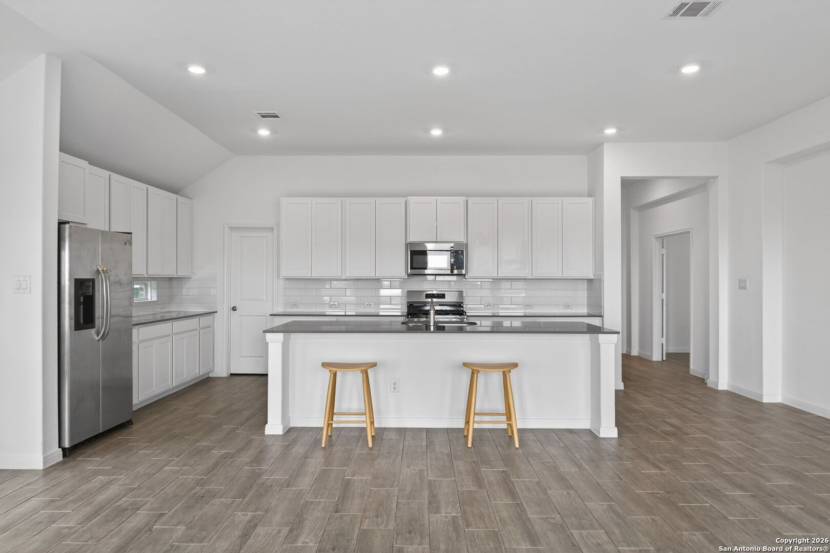 5755 Musquiz Ridge Seguin, TX 78155 - Photo 12 of 31 a kitchen with stainless steel appliances granite countertop a white cabinets and wooden floors