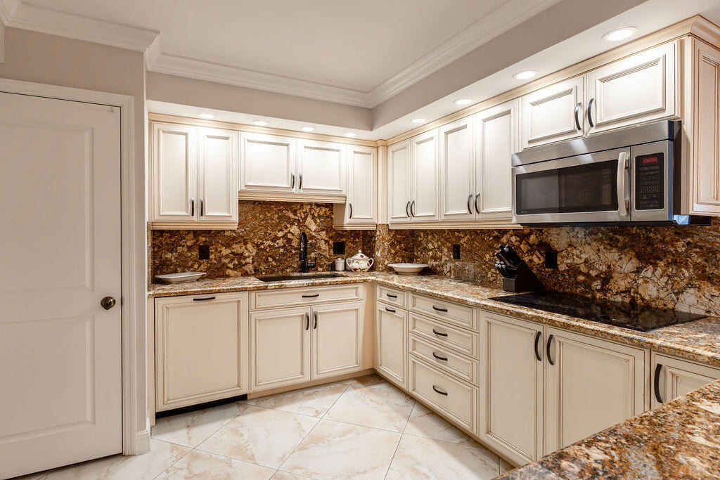 875 East Camino Real Boca Raton, FL 33432 - Photo 4 of 31 a kitchen with stainless steel appliances granite countertop white cabinets and window