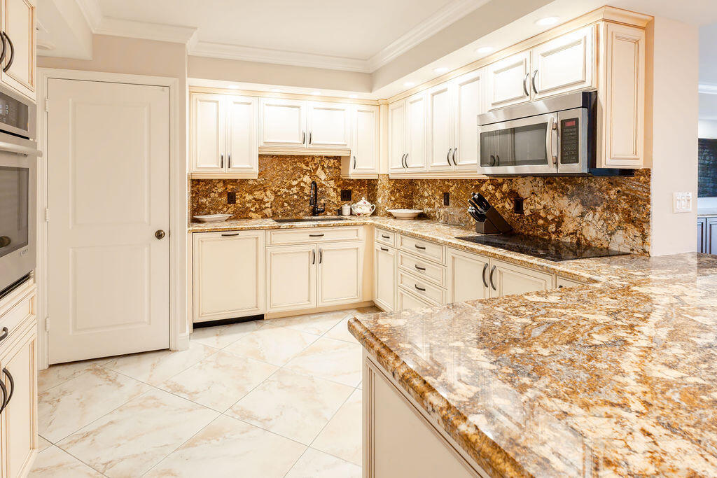 875 East Camino Real Boca Raton, FL 33432 - Photo 7 of 31 a kitchen with granite countertop a stove a sink and a refrigerator