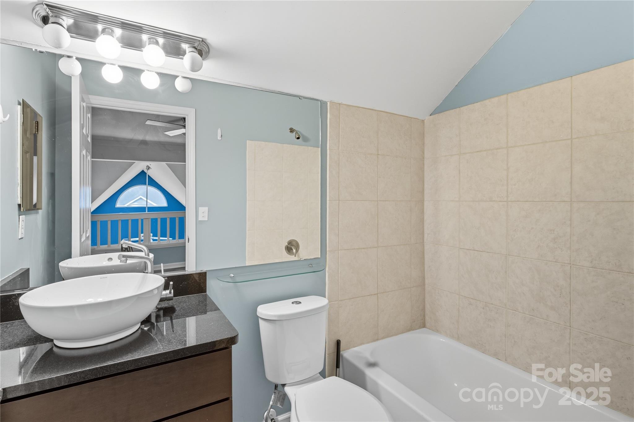 509 North Graham Street, Unit 3J Charlotte, NC 28202 - Photo 12 of 32 a bathroom with a granite countertop sink mirror vanity and toilet