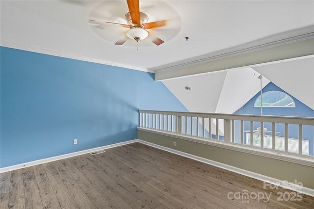 an empty room with wooden floor fan and windows