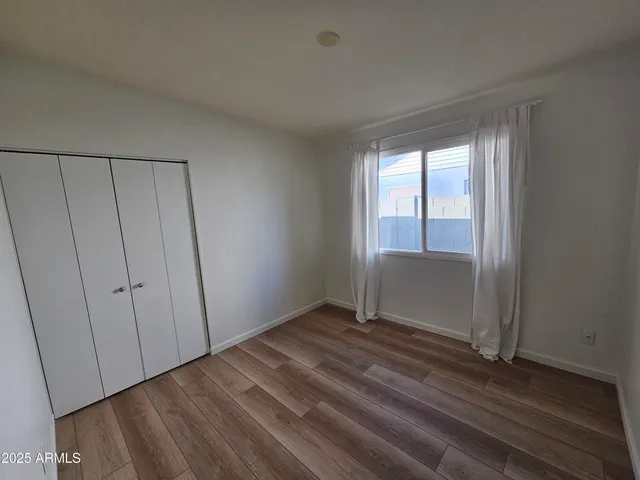 an empty room with wooden floor and a hallway