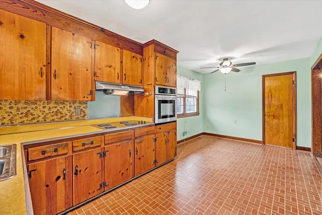 a view of a kitchen with stainless steel appliances wooden floor and chandelier