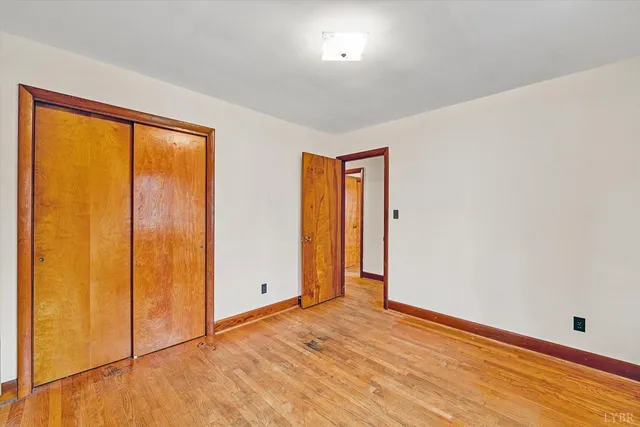 an empty room with wooden floor and closet area