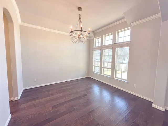 an empty room with a chandelier fan and windows