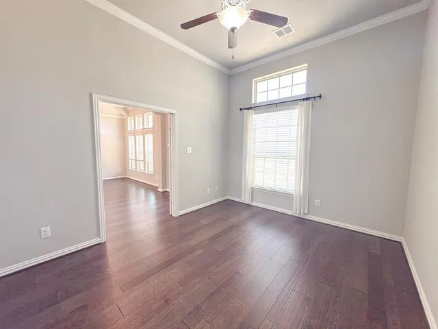 a view of an empty room and window with a ceiling fan