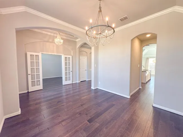 a view of an empty room with wooden floor and window