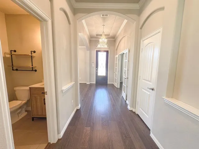 a view of a hallway with wooden floor and a bathroom