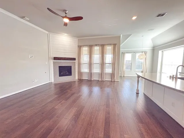 an empty room with wooden floor fireplace and windows