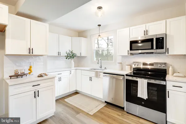 a kitchen with stainless steel appliances white cabinets and a stove top oven
