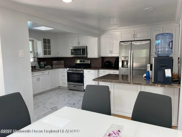 a kitchen with stainless steel appliances kitchen island granite countertop a refrigerator a stove top oven and a sink