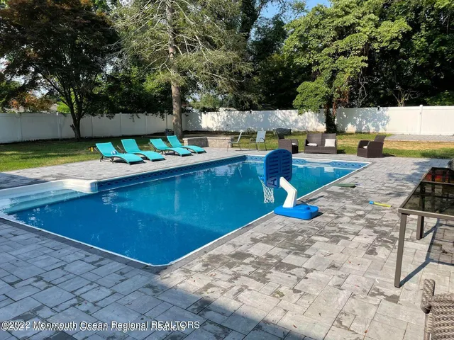 a view of a backyard with table and chairs potted plants and large tree